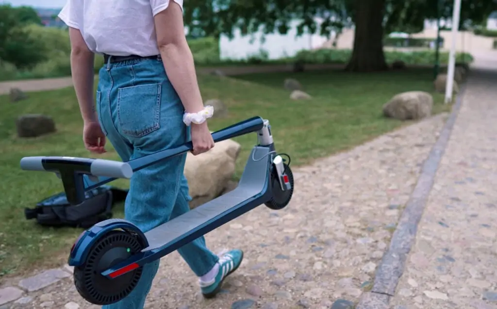 girl carrying an unagi model one e500 electric scooter