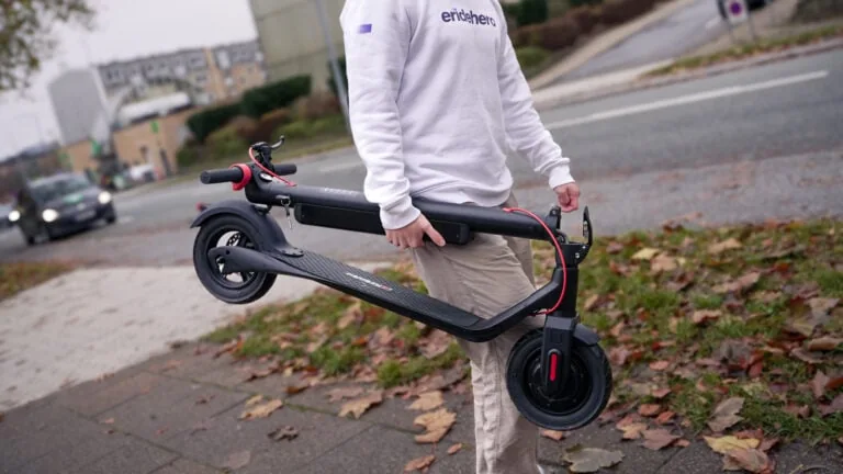 Rasmus from ERideHero carrying a folded electric scooter with one hand