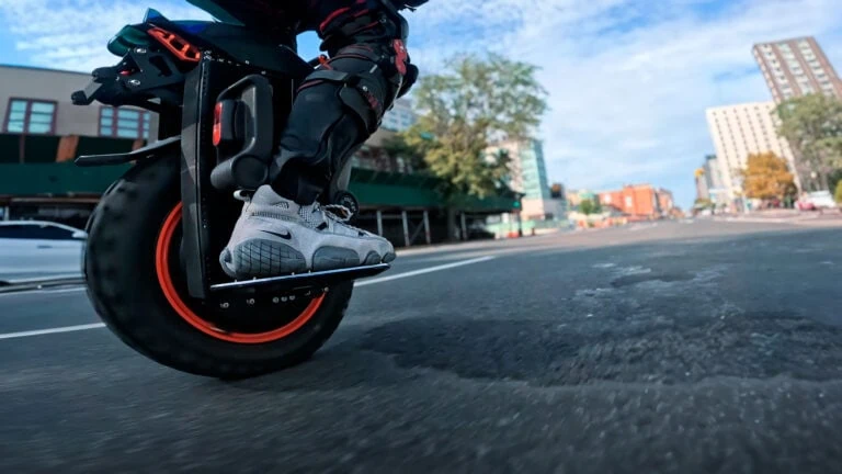 Rider on an electric unicycle gliding through city streets with urban buildings in the background